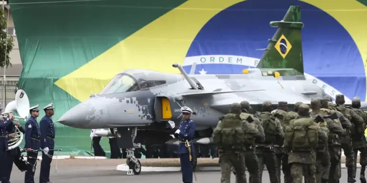 Militares em formação diante de aeronave da Aeronáutica com bandeira do Brasil ao fundo, representando novo edital autorizado com 489 vagas.