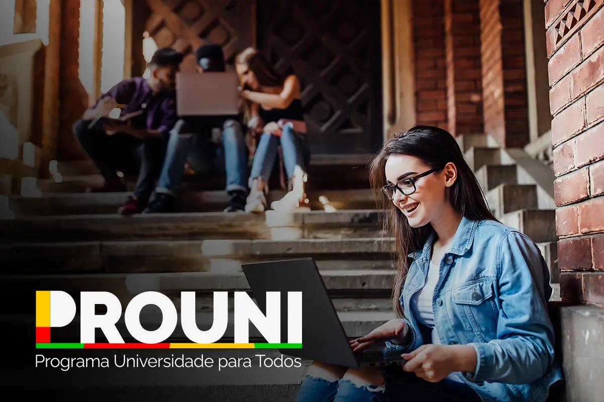 Como confirmar participação na lista de espera do Prouni 2026 Estudante usando notebook em escadaria enquanto acessa informações sobre o ProUni, programa que oferece bolsas de estudo em universidades privadas.