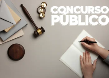 Martelo de juiz e mãos escrevendo em caderno com texto Concurso Público representando concurso da Câmara de Domingos Martins ES