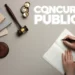 Martelo de juiz e mãos escrevendo em caderno com texto Concurso Público representando concurso da Câmara de Domingos Martins ES