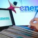 Mão segurando caneta sobre cadernos com notebook aberto exibindo logomarca do ENEM