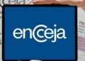 Mão segurando tablet com logo do Encceja e folha de redação ao fundo