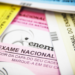 Cadernos de provas coloridos do Enem sobre mesa — Enem ganha novo papel e avaliará nível da educação nacional