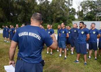 Instrutor aponta para grupo de candidatos da Guarda Municipal em formação ao ar livre