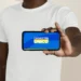 Homem negro de camiseta branca segura smartphone horizontal com tela do aplicativo Cadastro Único para Programas Sociais do Governo Federal
