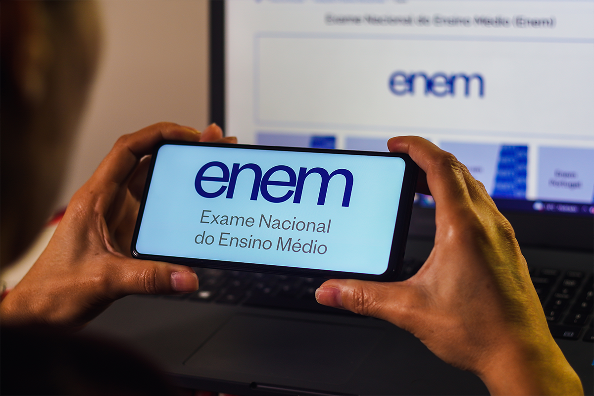 Calendário completo isenção Enem 2026 - datas e prazos para solicitação Mãos segurando smartphone com aplicativo do Enem Exame Nacional do Ensino Médio
