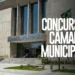 Prédio moderno da Câmara Municipal com fachada em concreto, escadaria central e bandeira do Brasil hasteada