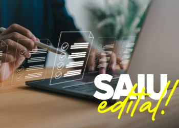 Pessoa usando notebook com texto "Saiu Edital!" em destaque