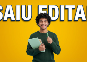 Jovem negro de cabelo cacheado segura cadernos verdes e caneta, sorrindo, com texto "SAIU EDITAL" em fundo amarelo