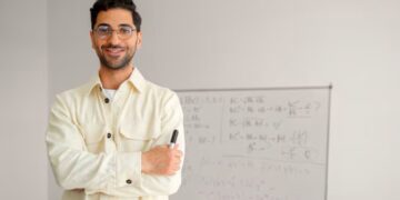 Professor em sala de aula com quadro ao fundo