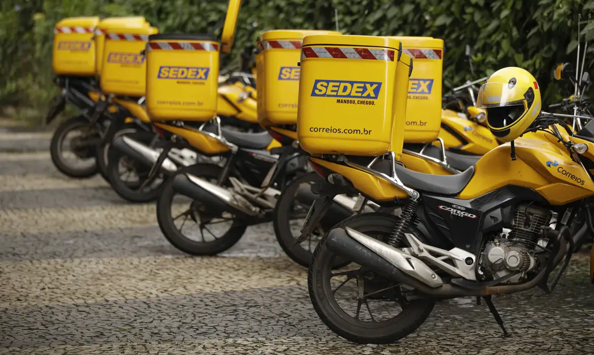 Convocação concurso correios Motos amarelas dos Correios alinhadas com baús SEDEX e capacetes em área externa
