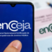 Tela de celular com logo do Encceja e prova impressa ao fundo sobre mesa