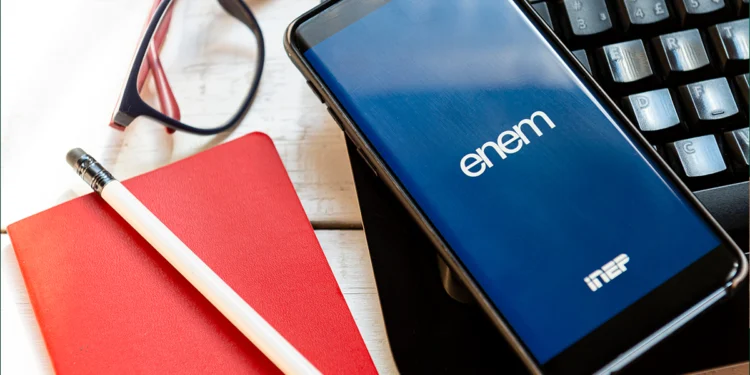 smartphone com aplicativo do Enem INEP sobre caderno vermelho e teclado