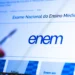 Tela do site do ENEM com logo azul, texto "Exame Nacional do Ensino Médio" e mão apontando caneta para o monitor