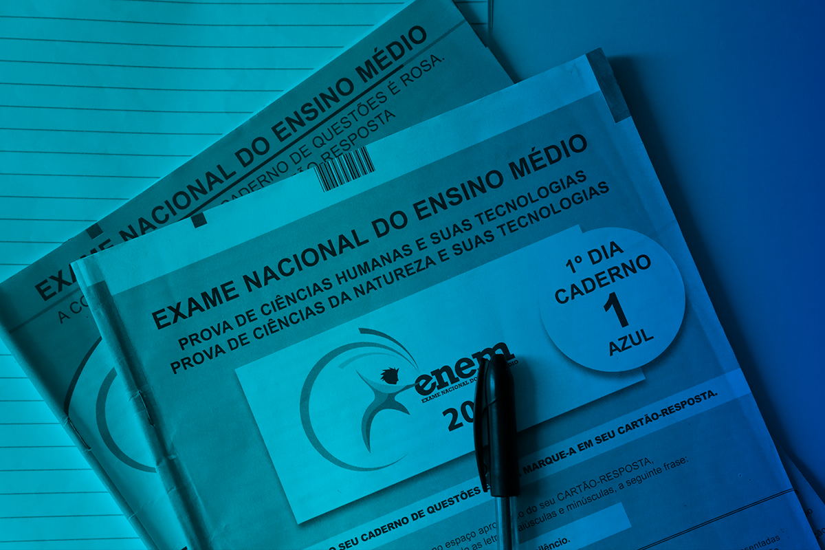 Preparação Enem 2026 Cadernos de prova do ENEM empilhados com caneta preta, mostrando capa azul do 1º dia com logo oficial