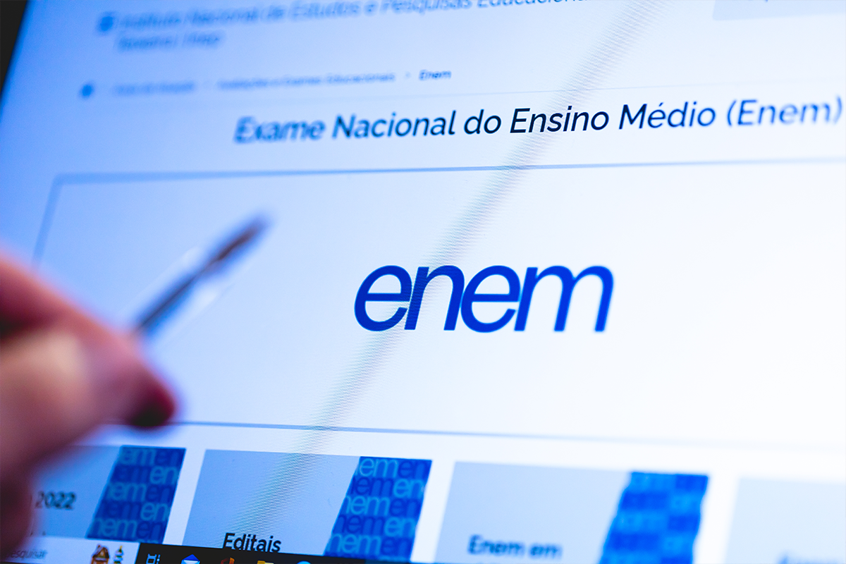 Recurso da isenção do Enem 2026: veja o prazo Tela de computador exibindo o site oficial do ENEM com logotipo azul e seção de editais visível, mão com caneta em primeiro plano.